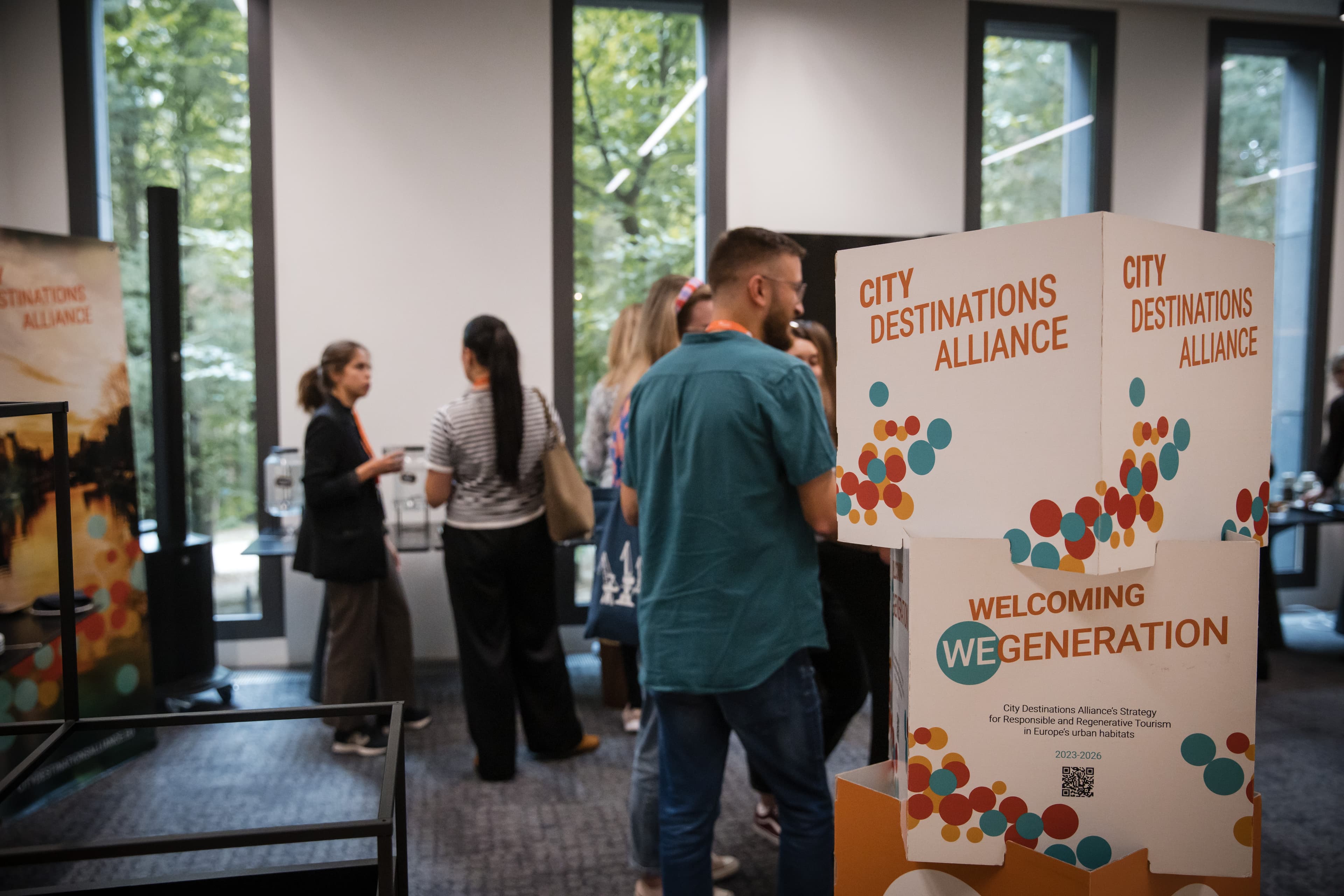 Attendees at a coffee break beside a City Destinations Alliance branded display