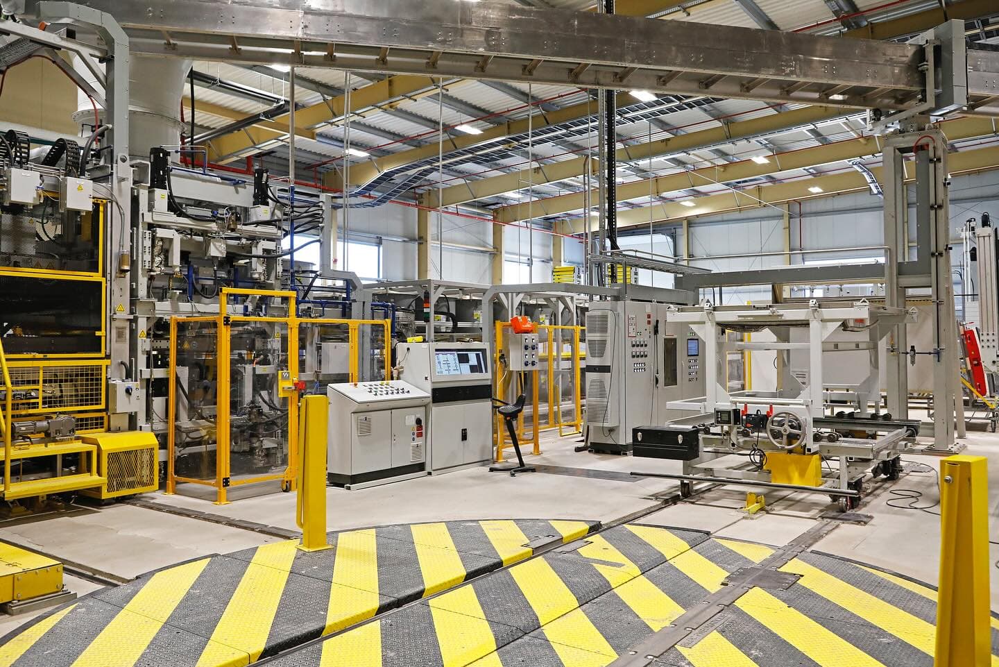 Interior of a modern industrial production hall with machinery and yellow safety markings
