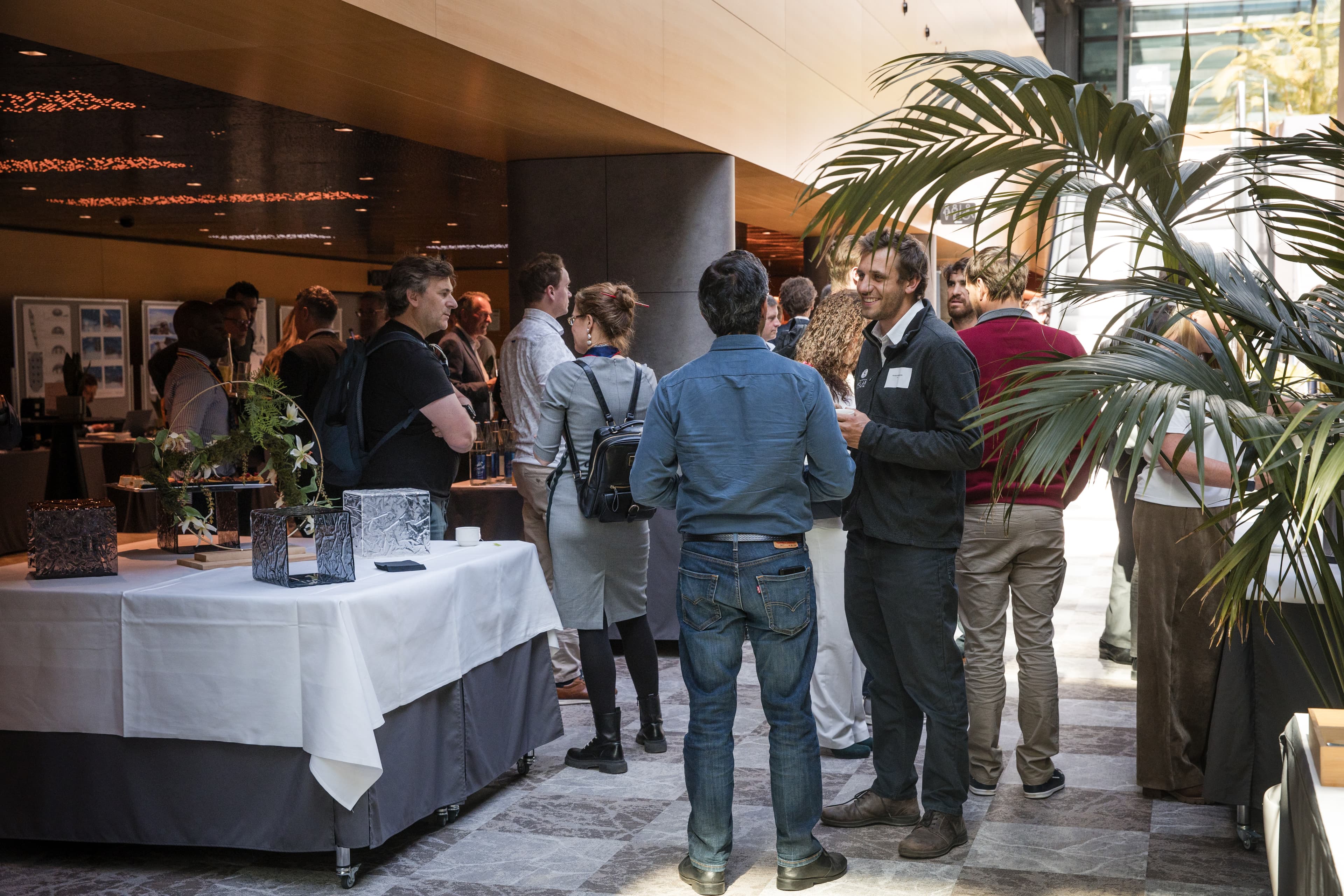 Attendees networking during a break in a bright venue foyer with a decorated buffet table