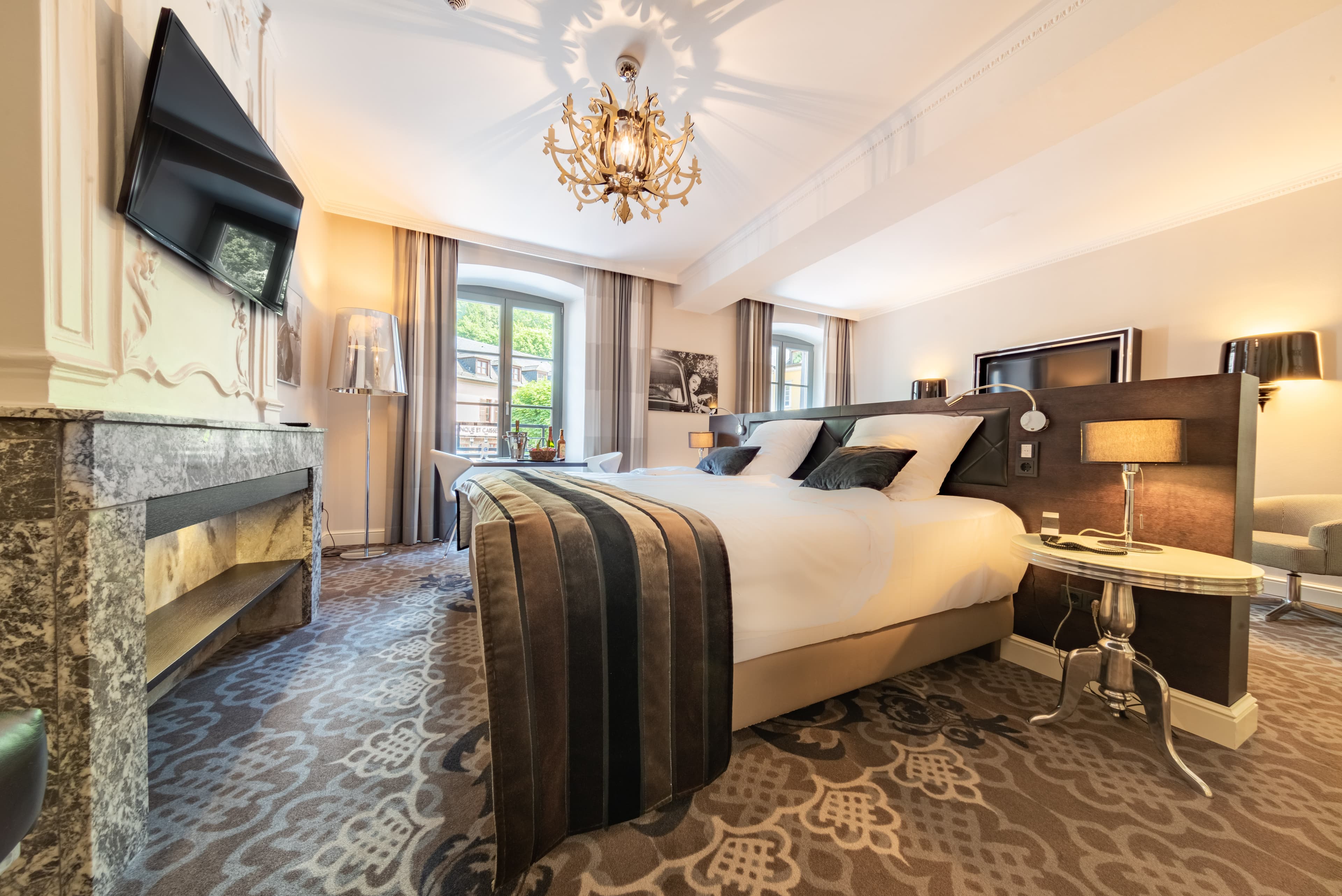 Elegant hotel bedroom with a double bed, chandelier and marble fireplace